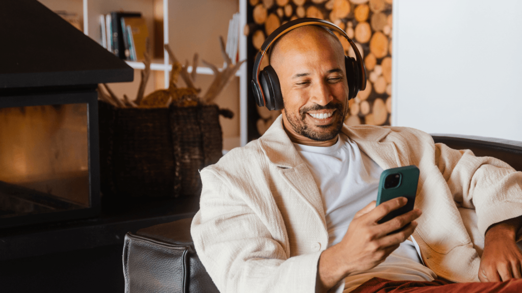Man relaxing with headphones while researching junk bonds on his phone