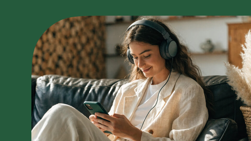 A woman sitting on a leather chair and looking at her mobile screen, researching best ways to invest 10k.