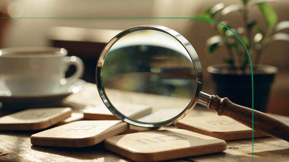 Magnifying glass examining wooden tiles on a table, symbolizing how to find the best stocks through careful research